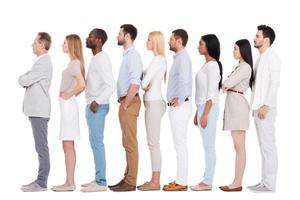 Standing in a row. Full length of confident multi-ethnic group of people in smart casual wear looking away while standing in a row and against white background photo