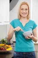 Cheerful housewife. Mature blond hair woman mixing something in a mixing bowl and smiling at camera photo