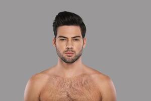 Real man. Handsome young man looking at camera while standing against grey background photo