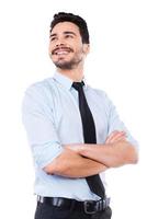 Young and full of energy. Low angle view of handsome young man in shirt and tie holding hand on chin and smiling while standing against white background photo