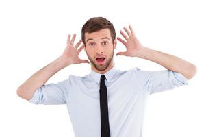 noticias impactantes. sorprendido joven con camisa y corbata expresando positividad y gesticulando mientras está de pie aislado en blanco foto