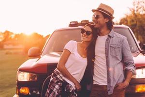 Thinking about new place to go. Beautiful young smiling couple looking thoughtful while bonding to each other and leaning at their pick-up truck photo