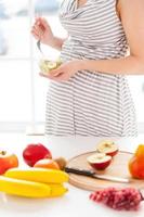 único alimento saludable para mi bebé. imagen recortada de una mujer embarazada comiendo una ensalada de frutas foto