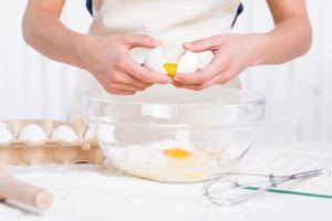 Cracking an egg to a bowl. Close-up of woman cracking egg for pastry photo
