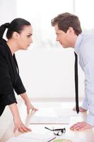 Business confrontation. Young man and woman in formalwear looking at each other and expressing negativity while standing face to face photo