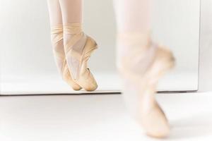 Dancing in Pointe. Close-up of ballerina legs in slippers standing against mirror photo