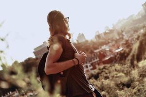 asombrado por la belleza. joven con ropa informal mirando la vista mientras está de pie en la colina al aire libre foto