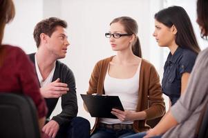 I have an issue. Group of people sitting close to each other while man telling something and gesturing photo