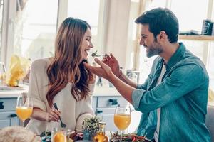 Beautiful young couple enjoying healthy breakfast while sitting in the kitchen at home photo