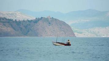 pescador no barco com varas de pesca flutua no mar video