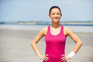 Confident and sporty. Handsome young man in sports clothing holding hands on hip while standing outdoors photo