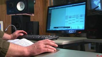 el sonido se sienta frente a un monitor y graba música en su computadora video