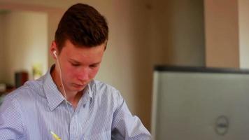 teenager boy sitting indoor with headphones and using computer video