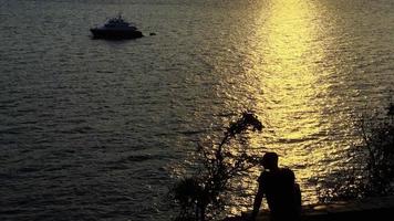mensen silhouet in de buurt de zee in zonsondergang licht