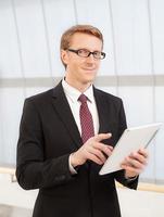 Confident and intelligent. Confident young man in formalwear holding a digital tablet and looking at camera photo