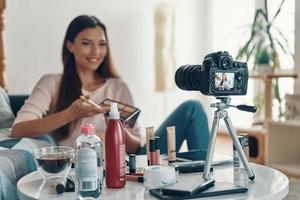 Happy young woman applying make-up palette and smiling while making social media video photo