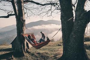 Attractive young woman lying in hammock while camping with her boyfriend photo