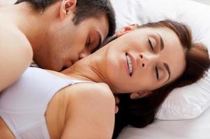 I love him kissing me Beautiful young loving couple having sex while lying in bed photo