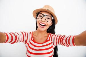 Selfie fun. Happy young women making selfie on camera while standing against white background photo