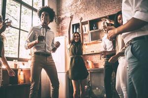 bailar es todo lo que necesitamos vista en ángulo bajo de jóvenes alegres bailando y bebiendo mientras disfrutan de una fiesta en casa en la cocina foto