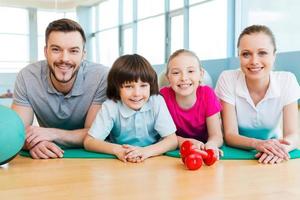 Sporty family. Happy sporty family bonding to each other while lying on exercise mat together photo