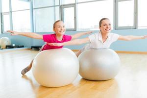 haciendo ejercicio con pelotas de fitness. alegre madre e hija haciendo ejercicio con pelotas de fitness y sonriendo foto