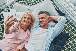 vista superior de una hermosa pareja madura haciendo selfie por teléfono inteligente y sonriendo foto