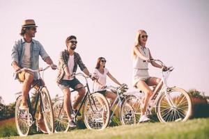 Cycling with best friends. Group of young people riding bicycles and looking happy photo