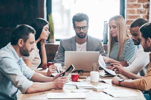 Time to familiarize new business plan Group of six young people reading and looking threw charts while sitting at the table in office photo