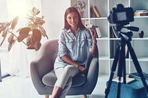 Shi is an expert. Attractive young woman showing beauty product while making new video indoors photo