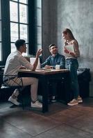 Group of young modern people in smart casual wear discussing something while working in office photo