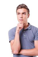 Thoughtful handsome. Thoughtful young man holding hand on chin and looking away while standing isolated on white background photo