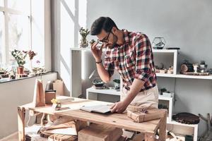 otra entrega. apuesto joven ajustando sus gafas y mirando en su organizador personal mientras está de pie en el interior foto