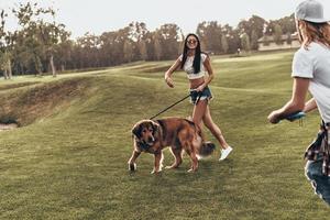 Carefree time together. Full length of beautiful young couple playing with their dog while spending time outdoors photo