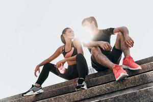 Lucky to have each other. Young couple in sport clothing looking at each other while sitting on the stairs outdoors photo