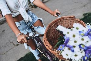 Feeling the road. Close-up of young woman in casual wear riding on a bicycle while spending carefree time outdoors photo