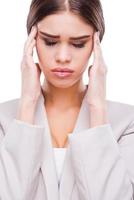 Feeling exhausted. Depressed young businesswoman touching her face and keeping eyes closed while standing against white background photo