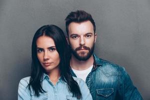 Beautiful couple. Portrait of beautiful young couple in jeans wear looking at camera while standing against grey background photo