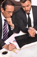 Business people at work. Top view of two business people in formalwear discussing something while one of them pointing computer monitor photo