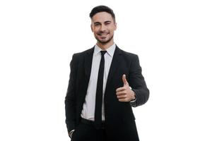 un joven apuesto con traje completo gesticulando y sonriéndote mientras está de pie contra el fondo blanco foto