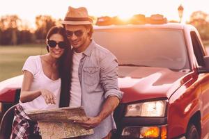 Examining map together. Beautiful young couple bonding to each other and leaning at their pick-up truck while examining map together photo