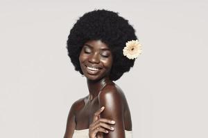 Portrait of beautiful young African woman touching shoulder and smiling photo