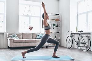 mantenerse en forma y saludable. bella joven asiática vestida con ropa deportiva haciendo yoga mientras se relaja en casa foto