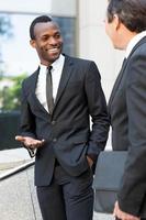 Discussing business. Two cheerful business men talking and gesturing while standing outdoors photo