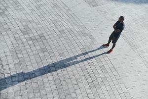 todos los días llenos de deporte. vista superior del joven africano en ropa deportiva manteniendo los brazos cruzados mientras está de pie al aire libre foto