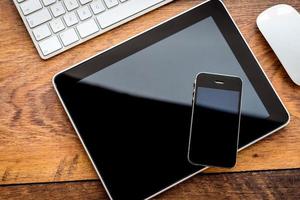 Full interaction. Top view of digital tablet and mobile phone laying on wooden table photo