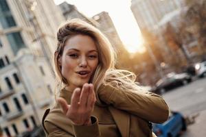 suave sensualidad. mujer joven atractiva mirando a la cámara y sonriendo mientras está de pie al aire libre foto