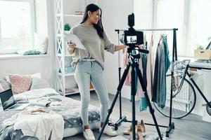 Beautiful young woman in casual clothing making social media video while spending time at home photo