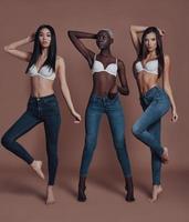 Dangerously beautiful. Full length of three attractive young women looking at camera while standing against brown background photo