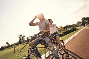 juguetón y lleno de amor. hermosa pareja joven en ropa casual en bicicleta juntos mientras pasan tiempo sin preocupaciones al aire libre foto